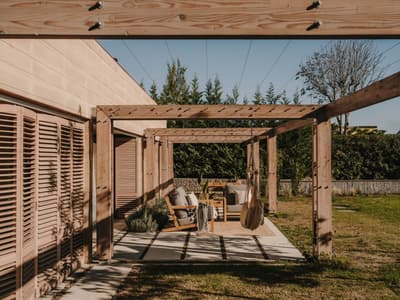 Architectural project - wooden shutters, outdoor lounge, wooden pergola, timber pergola, garden terrace, patio seating, outdoor furniture, al fresco, garden decor, landscaped garden, sustainable materials, wood, timber, relaxed vibe, natural light, outdoor living, warm tones, eco design, outdoor area, neutral tones, beige, natural setting, timber construction, rustic modern, wood structure, timber walls, modern rustic, earthy tones, warm atmosphere, cozy outdoor, garden design, relaxing space, garden retreat, landscape design, sunny day, backyard retreat, garden view, nature integration, outdoor shelter, open air, lounge chairs, comfortable seating, inviting exterior, garden seating, residential garden, home garden, green space