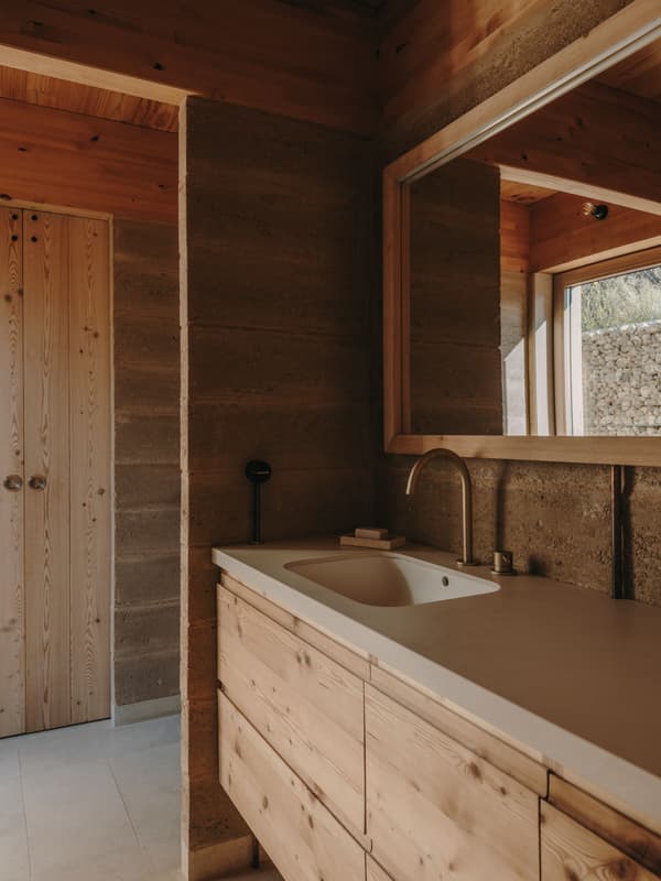 Architectural project - rustic elegance, rammed earth walls, natural bathroom, rustic bathroom, wood bathroom, minimal bathroom, wooden vanity, timber vanity, countryside style, handcrafted feel, natural materials, soft lighting, wood, timber, natural light, sustainable design, warm tones, eco design, daylight, beige, brown, concrete, light wood, eco friendly, Scandinavian influence, simple design, honey wood, natural textures, rustic charm, serene atmosphere, neutral palette, calming space, minimalist design, rammed earth, modern rustic, passive house, natural ventilation, Nordic design, cozy vibe, stone, beige tones, timber interior, earthy tones, nature-inspired, peaceful retreat, earthy textures, open window, wood interior