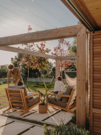 Architectural project - backyard lounge, cozy patio, modern patio, wooden pergola, timber pergola, garden chairs, hammock, garden pergola, timber posts, peaceful garden, residential outdoor, open air space, garden relaxation, garden furniture, leisure area, wood, timber, outdoor space, warm sunlight, natural light, outdoor living, sustainable design, natural tones, beige, brown, natural setting, retreat space, serene atmosphere, casual seating, relaxation spot, outdoor seating, earthy tones, eco friendly space, landscape design, lounge chairs, wooden structure, private garden, patio furniture, green space, laid-back vibe, family area