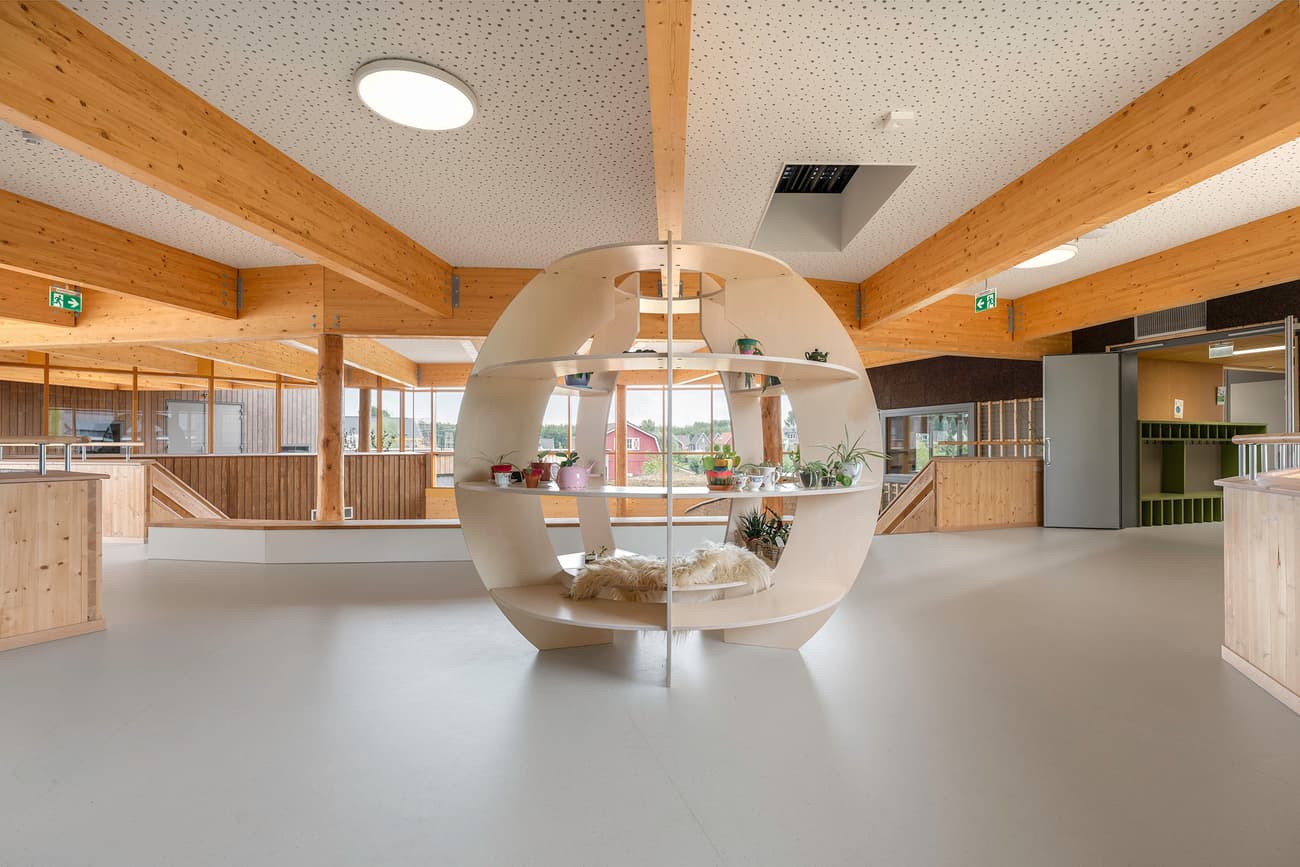 Architectural project - raw aesthetic, welcoming atmosphere, Nordic touch, plants, relaxed environment, wood building, inviting, curved shelving, display unit, centerpiece, spacious, circular element, vibrant, playful, natural materials, soft lighting, wood, timber, warm tones, contemporary style, sustainable architecture, exposed beams, daylight, plywood, gathering space, beige, light wood, natural wood, multifunctional space, eco friendly, modern design, honey wood, minimalist vibe, neutral palette, community center, light tones, timber panels, biophilic design, light filled, wood cladding, cozy nook, timber interior, greenery, Scandinavian design, seating area, bright interior, open space, public building, organic shapes, indoor plants, high ceiling, airy