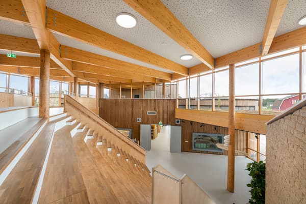 Architectural project - spacious design, amphitheater, stepped seating, acoustic design, structural elegance, modern venue, warm interior, indoor space, wood, timber, natural light, inviting atmosphere, passive design, sustainable design, contemporary style, neutral tones, exposed beams, timber structure, daylight, plywood, gathering space, beige, brown, light wood, engineered wood, multifunctional space, eco friendly, honey wood, wood beams, Scandinavian style, social space, community hub, community center, eco building, wood structure, circular design, natural ventilation, light filled, timber cladding, wood cladding, white, modern architecture, Nordic style, timber ceiling, open plan, green design, bright interior, open space, educational space, public building, welcoming space, wooden walls