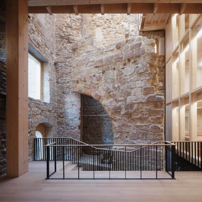 Architectural project - metal railing, exposed stone, cozy ambiance, rustic elegance, harmonious blend, glass enclosure, historic preservation, structural contrast, architectural heritage, black metal, historic renovation, wood, timber, metal, timber frame, natural light, inviting atmosphere, glass, warm tones, timber structure, daylight, beige, brown, light wood, honey wood, wood beams, rustic charm, neutral palette, black, adaptive reuse, wood floor, light filled, earthy materials, stone, airy space, open plan, stone wall, heritage building, timeless design, architectural contrast, double height, stone texture