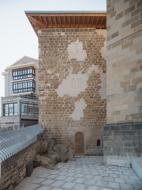 Architectural project - stone facade, natural stone, heritage preservation, rugged texture, historic building, cultural heritage, historical vibe, restoration, cobblestone path, heritage site, old building, medieval style, arched door, castle-like, wood, outdoor space, warm tones, neutral tones, beige, brown, durable materials, rustic look, timber roof, textured wall, stone, stonework, wood roof, traditional design, stone wall, exterior view, wooden door