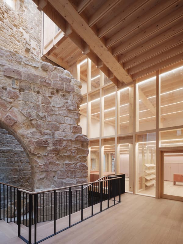 Architectural project - natural stone, stone cladding, loft style, cultural space, architectural heritage, historic charm, converted building, cozy interior, warm interior, soft lighting, wood, timber, natural light, sustainable design, reclaimed materials, glass, warm tones, eco design, neutral tones, timber structure, daylight, beige, brown, light wood, golden, honey wood, wood beams, rustic modern, black, public space, adaptive reuse, industrial chic, exposed wood, modern rustic, large windows, stone, open layout, open plan, inviting space, stone wall, heritage building, glass facade, architectural contrast, mixed materials, texture contrast, high ceiling, double height