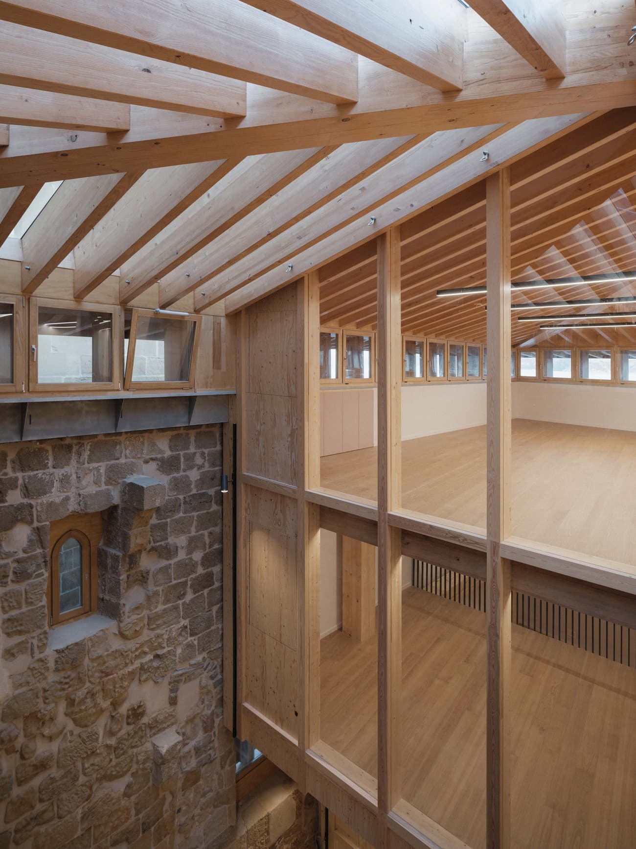 Architectural project - open ceiling, rustic stone, modern addition, textural contrast, multipurpose space, cozy interior, warm interior, natural materials, wood, timber, natural light, passive design, sustainable design, glass, warm tones, eco design, neutral tones, timber structure, exposed beams, daylight, beige, brown, light wood, honey wood, timber beams, light brown, timber floor, adaptive reuse, Scandinavian vibe, creative space, wood structure, wood floor, circular design, natural palette, modern rustic, biophilic design, timber cladding, wood cladding, Nordic style, stone, warm ambiance, rustic style, timber interior, open plan, inviting space, stone wall, heritage building, architectural harmony, architectural contrast, skylight, wood interior