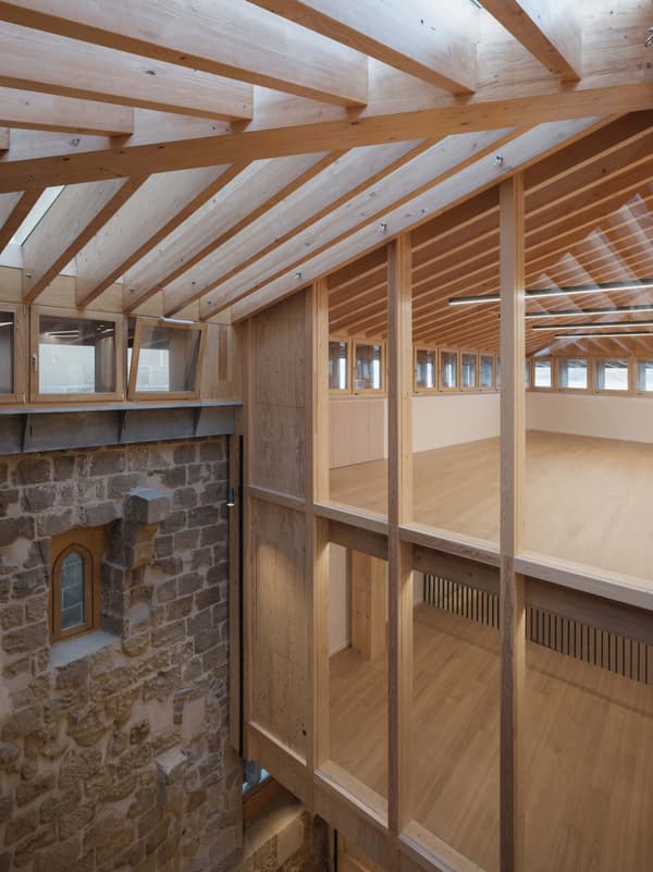 Architectural project - open ceiling, rustic stone, modern addition, textural contrast, multipurpose space, cozy interior, warm interior, natural materials, wood, timber, natural light, passive design, sustainable design, glass, warm tones, eco design, neutral tones, timber structure, exposed beams, daylight, beige, brown, light wood, honey wood, timber beams, light brown, timber floor, adaptive reuse, Scandinavian vibe, creative space, wood structure, wood floor, circular design, natural palette, modern rustic, biophilic design, timber cladding, wood cladding, Nordic style, stone, warm ambiance, rustic style, timber interior, open plan, inviting space, stone wall, heritage building, architectural harmony, architectural contrast, skylight, wood interior