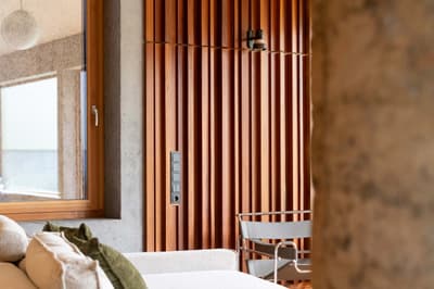Architectural project - exposed concrete, feature wall, accent wall, natural elements, relaxing vibe, timber slats, concrete column, interior decor, cozy interior, natural materials, wood, timber, natural light, sustainable design, warm tones, daylight, beige, concrete, light wood, eco friendly, contemporary design, industrial touch, Scandinavian style, neutral palette, casual seating, soft textures, biophilic design, passive house, Nordic style, textured wall, green home, wood slats, comfortable seating, minimalist aesthetic, modern furniture, calm atmosphere, lounge area, modern living, vertical slats, home improvement, modern interior, residential interior, living space, urban retreat