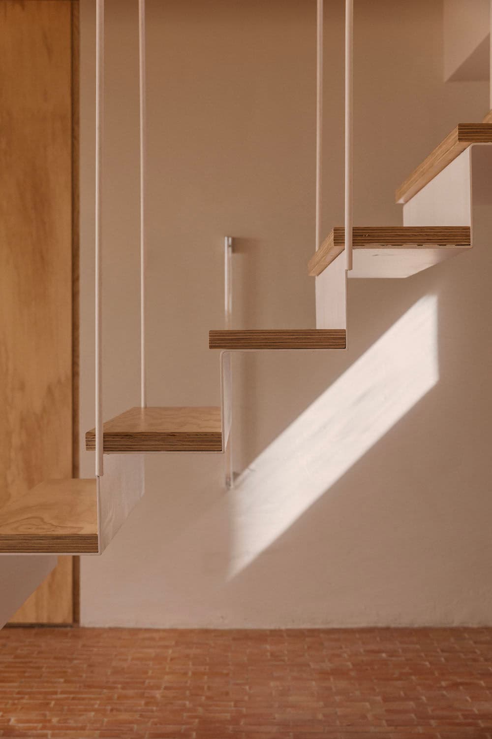 Architectural project - metal railing, minimalist stairs, modern staircase, urban loft, cozy feel, open risers, loft vibe, floating stairs, suspended stairs, wooden treads, white railing, oak wood, plywood steps, small stair, studio apartment, wood and metal, wood and brick, indoor space, architectural detail, metal, natural light, shadow play, sustainable design, warm tones, daylight, plywood, beige, light wood, compact space, Scandinavian style, light brown, neutral palette, minimalist design, eco-friendly materials, earthy texture, rustic texture, contemporary home, clean lines, white, airy space, warm atmosphere, terracotta, beige wall, sleek design, terracotta floor, Japandi style, residential interior