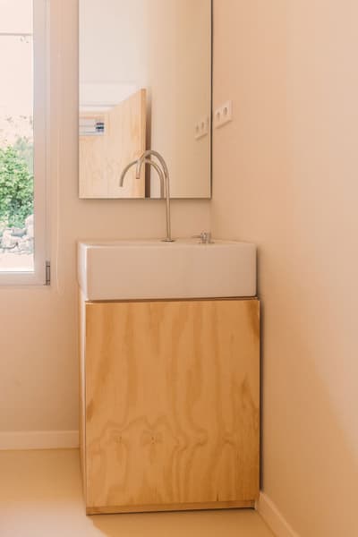 Architectural project - beige walls, space-saving, plywood cabinet, minimalist bathroom, compact bathroom, modern powder room, beige bathroom, plywood vanity, small sink, wall mirror, sustainable bathroom, bright bathroom, simple aesthetics, modern faucet, sleek fixtures, bathroom nook, contemporary bathroom, calming atmosphere, natural materials, tranquil space, eco-friendly design, natural light, natural tones, neutral tones, functional space, beige, light wood, Scandinavian style, minimalist design, clean lines, light filled, white, Nordic style, compact design, cozy corner, warm vibe, wooden texture, airy feel