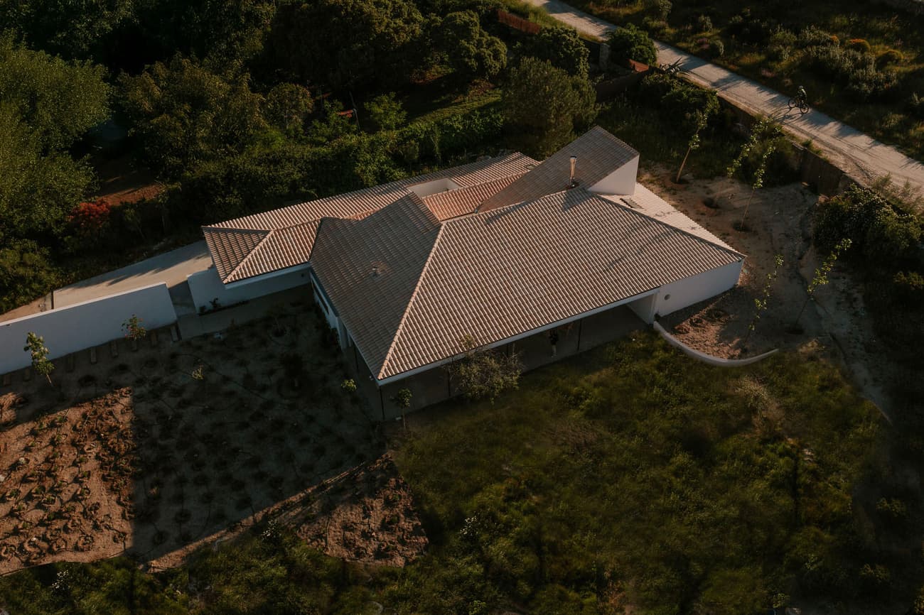 Architectural project - integration with nature, modern farmhouse, contemporary rural, terracotta roof, ceramic roof, modern rural architecture, unobtrusive design, subtle luxury, natural materials, eco-friendly design, outdoor space, passive design, warm tones, landscape architecture, beige, exterior design, rustic charm, private retreat, serene atmosphere, minimalist design, tranquil setting, natural landscape, natural ventilation, white facade, white walls, white, countryside home, rural living, earthy tones, pitched roof, garden design, terracotta, greenery, residential architecture, sustainable house, efficient layout, simple lines, environmentally conscious, organic shapes, aerial view, rural house, rural retreat, nature setting