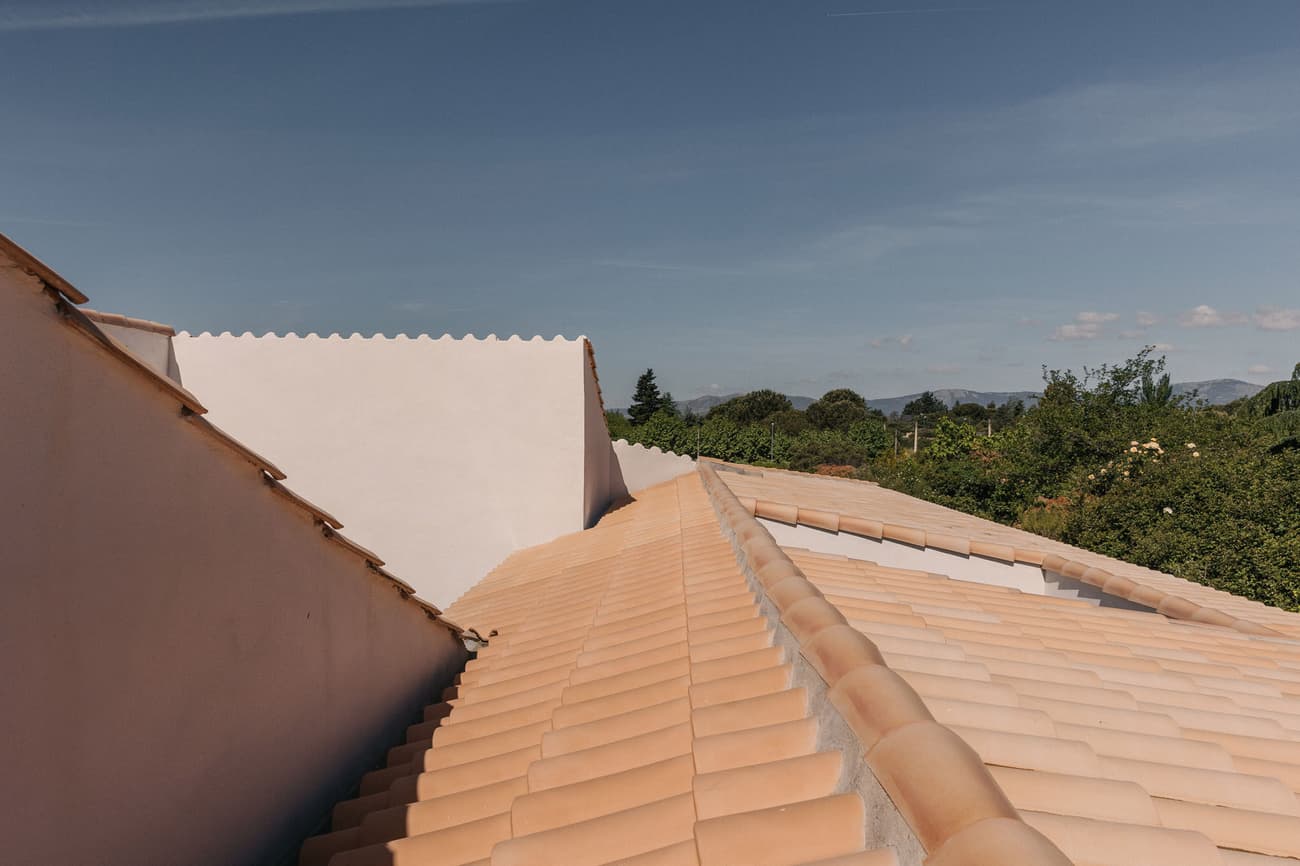 Architectural project - natural scenery, terracotta tones, terracotta roof, traditional roof, Southern European, minimalist roof, rustic vibes, sunny environment, roofscape, classic home, traditional construction, warm climate home, regional architecture, roofline, natural materials, outdoor space, sustainable design, warm tones, rural architecture, simple design, vernacular architecture, rustic charm, eco-friendly materials, earth tones, white walls, countryside home, landscape view, sloped roof, pitched roof, natural aesthetics, plaster finish, Mediterranean style, exterior view, serene landscape, pastoral scene, sky view, clay tiles, suburban house