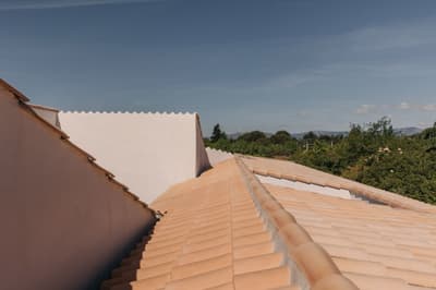 Architectural project - natural scenery, terracotta tones, terracotta roof, traditional roof, Southern European, minimalist roof, rustic vibes, sunny environment, roofscape, classic home, traditional construction, warm climate home, regional architecture, roofline, natural materials, outdoor space, sustainable design, warm tones, rural architecture, simple design, vernacular architecture, rustic charm, eco-friendly materials, earth tones, white walls, countryside home, landscape view, sloped roof, pitched roof, natural aesthetics, plaster finish, Mediterranean style, exterior view, serene landscape, pastoral scene, sky view, clay tiles, suburban house