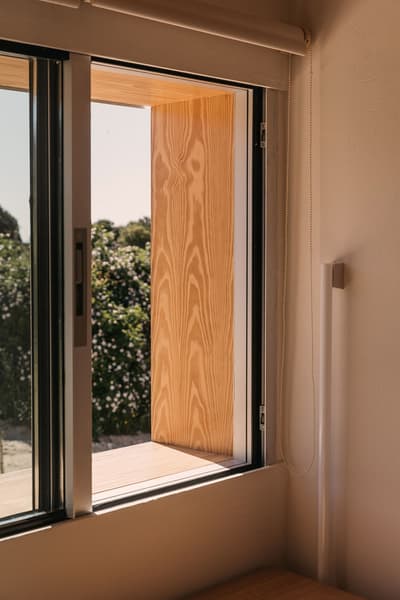 Architectural project - beige walls, linear design, transitional space, Scandinavian touch, timber shutter, wood shutter, sliding window, peaceful view, relaxation space, warm interior, wood, timber, natural light, passive design, glass, warm tones, natural tones, eco design, neutral tones, daylight, beige, light wood, honey wood, neutral palette, minimalist design, tranquil setting, sustainable home, natural ventilation, contemporary home, indoor outdoor, window view, glass window, landscape view, energy efficient, compact design, comfortable home, casual living, plaster finish, nature connection, cozy corner, garden view, modern living, simple lines, Japandi style
