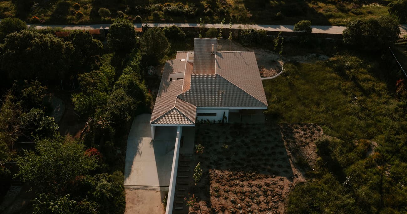 Architectural project - tiled roof, grey roof, roof tiles, spacious land, aerial house, countryside villa, large garden, outdoor garden, single-story house, driveway, entrance path, backyard garden, spacious property, garden oasis, farmhouse vibes, green tones, concrete path, relaxation space, natural materials, outdoor living, sustainable design, outdoor area, grey, landscape architecture, beige, daylight optimization, eco friendly, simple design, natural textures, low carbon, passive house, nature view, scenic view, green landscape, white, panoramic view, sloped roof, nature retreat, rural setting, landscape design, garden landscape, minimalist exterior, residential home, secluded home, private residence, modern home, contemporary house, garden path, home garden, cozy home, modern rural, suburban home, green space, green roof, aerial view, natural surroundings, rural retreat
