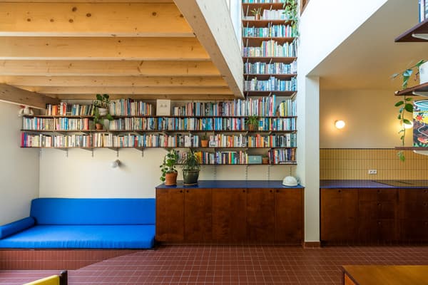 Architectural project - terracotta tiles, house plants, home sanctuary, relaxed environment, quiet space, blue sofa, library space, vibrant sofa, wall sconces, accent lighting, tile flooring, mid-century vibe, transitional style, bright color pop, cozy interior, natural materials, wood, timber, metal, natural light, inviting atmosphere, warm tones, eco design, neutral tones, exposed beams, daylight, brown, multifunctional space, blue, modern design, rustic charm, Scandinavian style, sustainable home, timber ceiling, warm ambiance, compact design, minimalist decor, terracotta, cozy corner, reading nook, home office, home library, wood cabinetry, efficient layout, nordic influence, wood ceiling, open shelving, built-in shelving, indoor plants, residential interior, dark wood