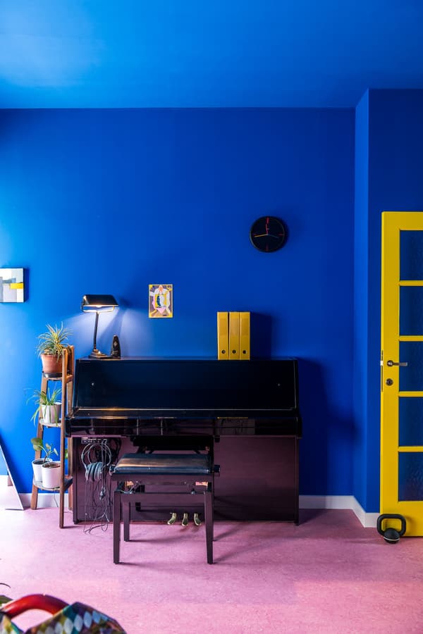 Architectural project - retro vibe, artistic vibe, bright blue, houseplants, eclectic decor, blue room, bold interior, vivid space, creative home, colorful walls, statement wall, piano corner, music room, pop art style, artistic home, striking contrast, yellow door, pink floor, inspiring space, conversational area, artistic expression, fusion style, neon yellow, black piano, music space, creative color, artistic flair, design trends, modern art, interior inspiration, pastel pink, playful design, eclectic style, modern design, relaxed atmosphere, vibrant colors, bright colors, creative space, contemporary home, open layout, cozy corner, home office, lounge area, indoor plants