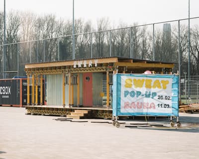 Architectural project - minimalist, relaxation space, timber, metal frame, grey, metal, sustainable design, glass, modular design, transparent walls, urban landscape, timber structure, neutral tones, public area, brown, industrial style, pop-up sauna, portable sauna, outdoor sauna, eco friendly, wood exterior, glass panels, recreational space, modern design, contemporary, temporary architecture, urban sauna, mobile wellness, steel framework, flat roof, boxy design, Scandinavian influence, open structure, airy design, compact space, natural setting, recreational architecture, wellness design, community use, eco structure, urban oasis, outdoor leisure