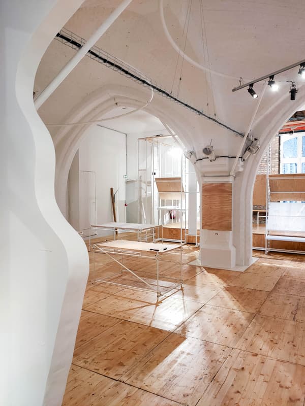 Architectural project - mixed-use space, creative studio, unfinished look, modern renovation, white interior, loft vibe, archways, art space, studio space, gallery setting, minimal design, architectural detail, wood, timber, raw materials, natural light, warm tones, exposed beams, plywood, beige, structural design, light wood, contemporary design, industrial touch, plywood floor, timber floor, neutral palette, adaptive reuse, workspace, wood floor, clean lines, white, airy space, open plan, spacious interior, Scandinavian design, bright interior, open space, airy atmosphere, modern interior, high ceiling, urban style, vaulted ceiling