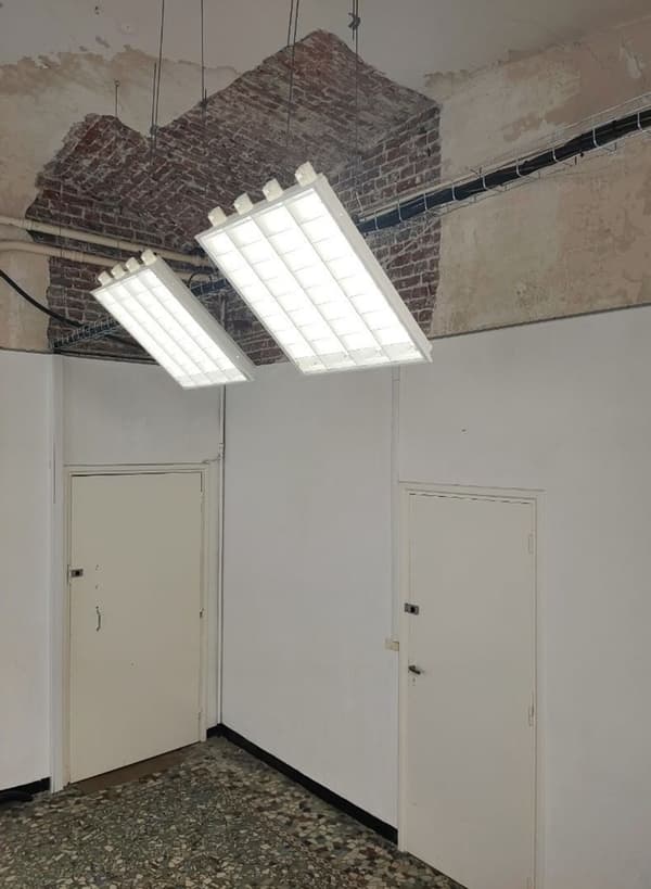 Architectural project - retro vibe, industrial interior, overhead lighting, creative studio, unfinished look, art studio, brickwork, exposed brick, fluorescent lights, ceiling lights, rustic industrial, industrial charm, speckled floor, utility room, utilitarian space, terrazzo floor, minimal design, natural materials, architectural detail, raw materials, grey, neutral tones, functional space, beige, concrete, simple design, rustic vibe, architectural lighting, neutral palette, industrial chic, creative space, workspace, raw texture, white walls, white, textured wall, plaster wall, raw finish, minimalist aesthetic, contrasting textures, urban style