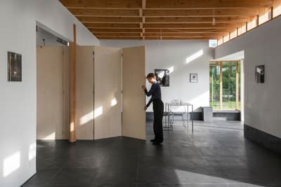 Architectural project - natural materials, eco-friendly design, wood, raw materials, grey, natural light, warm tones, exposed beams, daylight, plywood, timber ceiling, beige, concrete, light wood, multifunctional space, modern design, Scandinavian style, minimalist style, neutral palette, casual seating, biophilic design, sustainable home, clean lines, white walls, large windows, Nordic design, open plan, living area, simple living, outdoor connection, garden view, residential space, minimal interior, wood ceiling, folding partition, pivot door, concrete floor, dark tiles, floor-to-ceiling window, interior space, home interior, family room, contemporary aesthetic, open space, cozy home, airy atmosphere, black tiles, oak
