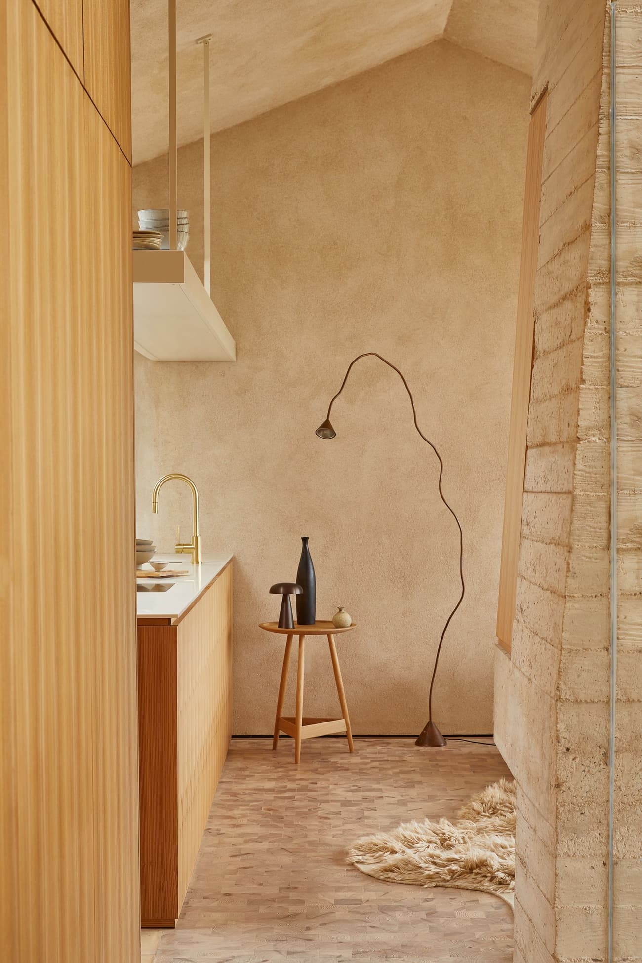 Architectural project - warm interior, natural materials, wood, timber, natural light, sustainable design, daylight, beige, light wood, eco friendly, compact space, honey wood, rustic modern, serene atmosphere, Scandinavian style, neutral palette, calming space, minimalist design, textured wall, plaster wall, plaster, cozy kitchen, open shelves, cozy corner, minimalist kitchen, simple decor, earthy textures, small kitchen, kitchen, Japandi style, Japanese style, woven rug, area rug, floor lamp, unique lamp, elegant decor, ceramic vase, rustic vase, wooden stool, smooth countertop, gold faucet, minimalist shelves, boho vibe, homey feel, warm tone, neutral tone, ceramic, natural, warm, wooden