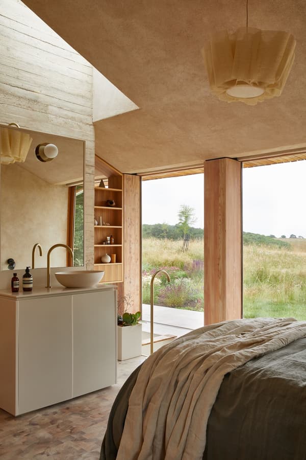 Architectural project - warm interior, calming atmosphere, natural materials, timber, natural light, sustainable design, glass, warm tones, neutral tones, daylight, beige, light wood, natural wood, rustic modern, natural textures, Scandinavian style, serene space, timber elements, modern rustic, eco home, passive house, clean lines, large windows, indoor outdoor, eco friendly home, textured wall, plaster wall, plaster, open layout, open plan, inviting space, earthy tones, Nordic vibe, warm light, countryside living, wooden accents, pendant light, wood paneling, bedroom retreat, cozy bedroom, rustic bedroom, minimalist bedroom, floor to ceiling, glass wall, soft textiles, linen bedding, simple furniture, connection to nature, pastoral views, wooden shelf, built-in shelving, hygge feel, tranquil retreat