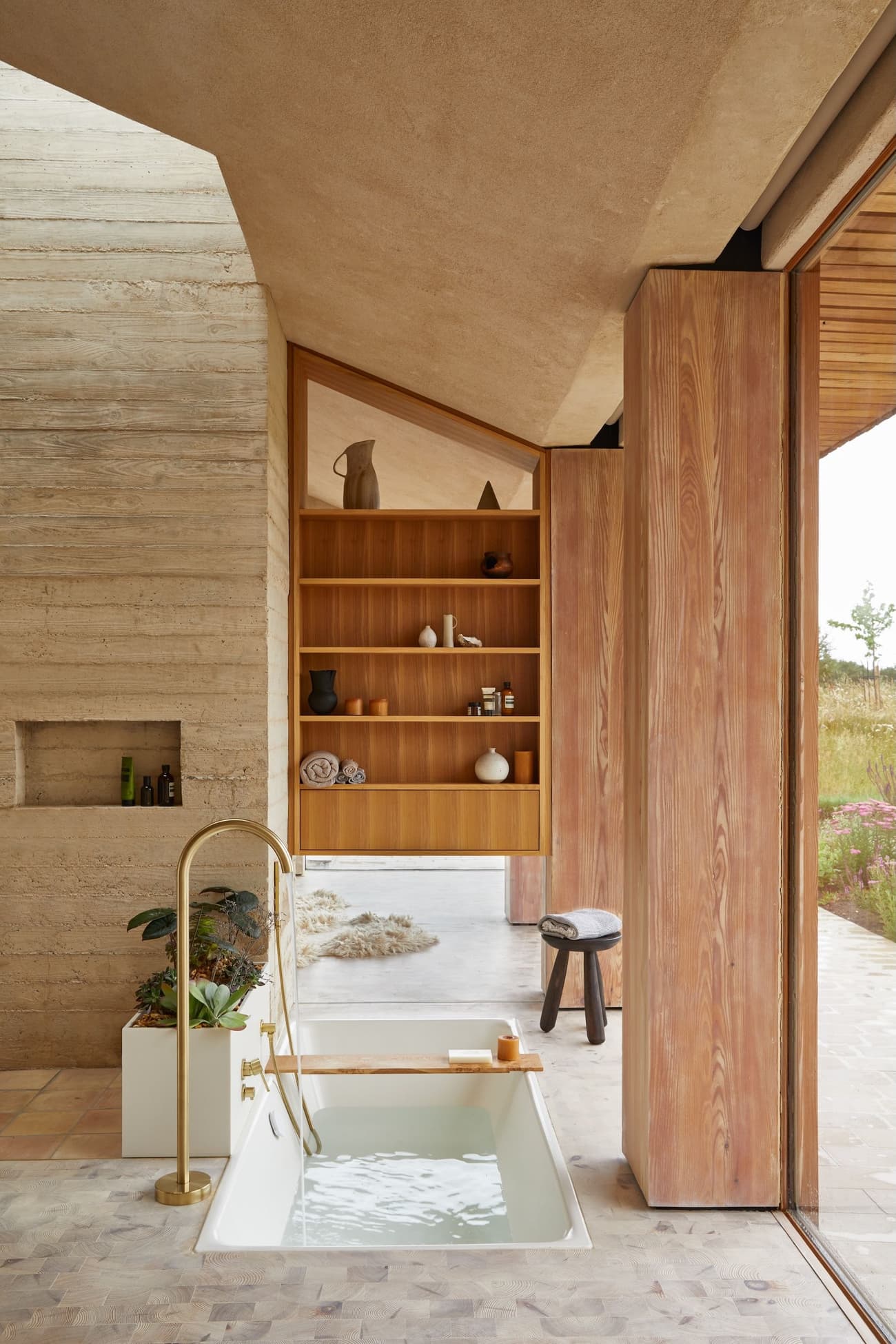 Architectural project - wellness space, warm interior, calming atmosphere, natural materials, soft lighting, wood, timber, natural light, sustainable design, glass, warm tones, neutral tones, daylight, beige, light wood, organic design, minimalist design, natural palette, biophilic design, cozy vibe, textured wall, stone, wood shelves, timber shelves, earthy tones, nature-inspired, relaxing space, peaceful retreat, stone floor, glass door, modern bathroom, soaking tub, recessed shelves, sliding door, warm materials, travertine floor, spa-like, concrete wall, serene bathroom, eco bathroom, indoor outdoor flow, indoor bathroom, open bathroom, travertine, wooden detailing, modern retreat, spa bath, elegant bath, natural finishes, zen decor, relaxing bath, luxurious bath