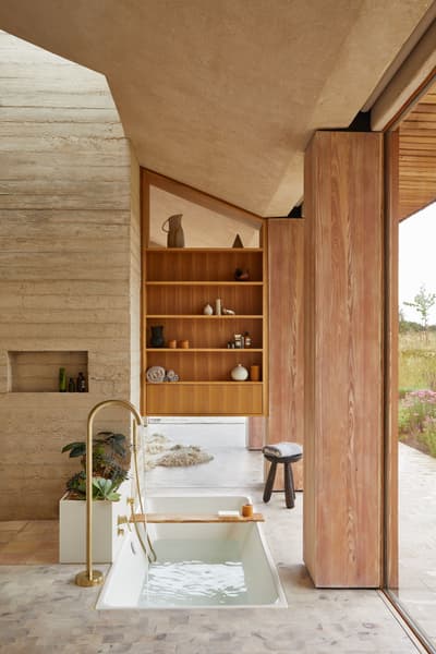 Architectural project - wellness space, warm interior, calming atmosphere, natural materials, soft lighting, wood, timber, natural light, sustainable design, glass, warm tones, neutral tones, daylight, beige, light wood, organic design, minimalist design, natural palette, biophilic design, cozy vibe, textured wall, stone, wood shelves, timber shelves, earthy tones, nature-inspired, relaxing space, peaceful retreat, stone floor, glass door, modern bathroom, soaking tub, recessed shelves, sliding door, warm materials, travertine floor, spa-like, concrete wall, serene bathroom, eco bathroom, indoor outdoor flow, indoor bathroom, open bathroom, travertine, wooden detailing, modern retreat, spa bath, elegant bath, natural finishes, zen decor, relaxing bath, luxurious bath