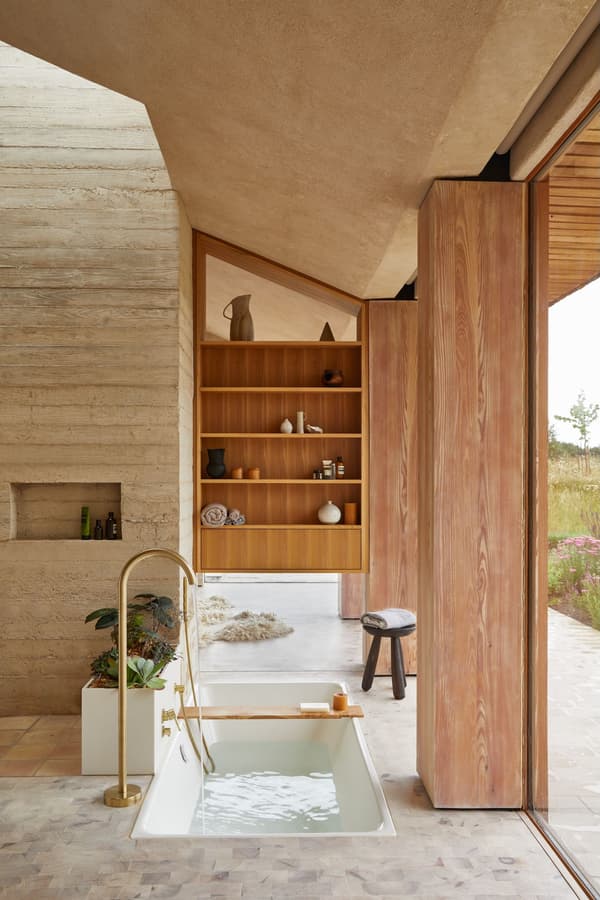 Architectural project - wellness space, warm interior, calming atmosphere, natural materials, soft lighting, wood, timber, natural light, sustainable design, glass, warm tones, neutral tones, daylight, beige, light wood, organic design, minimalist design, natural palette, biophilic design, cozy vibe, textured wall, stone, wood shelves, timber shelves, earthy tones, nature-inspired, relaxing space, peaceful retreat, stone floor, glass door, modern bathroom, soaking tub, recessed shelves, sliding door, warm materials, travertine floor, spa-like, concrete wall, serene bathroom, eco bathroom, indoor outdoor flow, indoor bathroom, open bathroom, travertine, wooden detailing, modern retreat, spa bath, elegant bath, natural finishes, zen decor, relaxing bath, luxurious bath