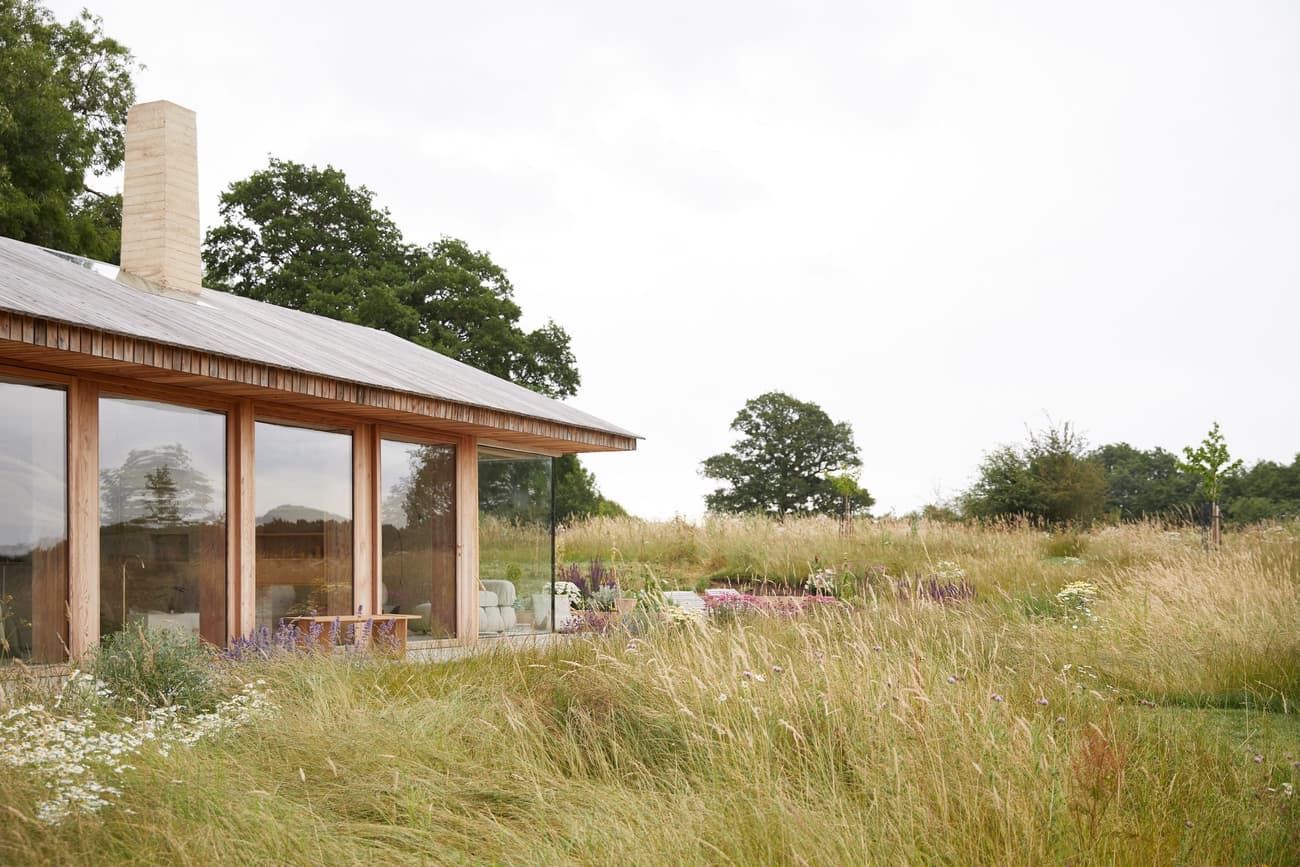 Architectural project - serene vibe, natural materials, wood, timber, timber frame, natural light, sustainable design, glass, warm tones, contemporary architecture, daylight, beige, eco friendly, modern design, flat roof, rural architecture, neutral palette, neutral colors, outdoor seating, warm wood, ecological design, open landscape, eco home, passive house, landscape integration, indoor outdoor, wood cladding, countryside home, beige tones, nature connection, tranquil environment, peaceful retreat, country living, low carbon building, wooden exterior, glass facade, site-specific design, natural surroundings, rural house, modern cabin, expansive windows, seamless view, exterior space, green roof potential, rural retreat, countryside setting, earthy colors, minimalist lines, relaxing home