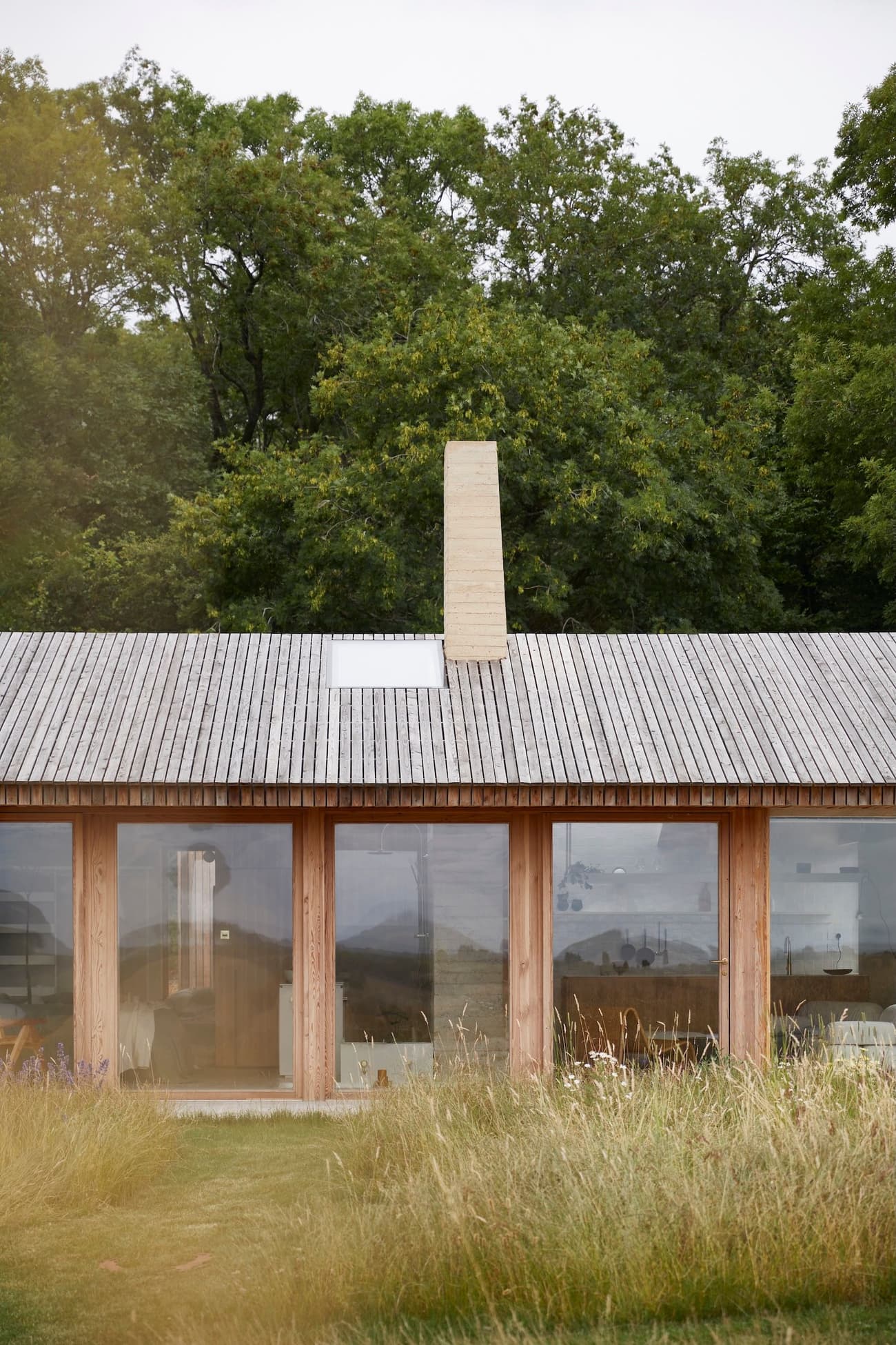 Architectural project - natural materials, wood, timber, grey, natural light, sustainable design, glass, natural tones, neutral tones, daylight, beige, wood facade, timber facade, light wood, eco friendly, honey wood, rustic modern, serene atmosphere, minimalist design, low carbon, modern rustic, biophilic design, open landscape, passive house, nature view, clean lines, large windows, indoor outdoor, timber cladding, wood cladding, Nordic style, energy efficient, earthy tones, sloped roof, pitched roof, wooden roof, peaceful vibe, wooden structure, green surroundings, simple lines, glass facade, rural house, country home, glazing, meadow, Scandinavian inspiration, elongated form, integrated architecture, connection with nature