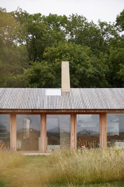 Architectural project - natural materials, wood, timber, grey, natural light, sustainable design, glass, natural tones, neutral tones, daylight, beige, wood facade, timber facade, light wood, eco friendly, honey wood, rustic modern, serene atmosphere, minimalist design, low carbon, modern rustic, biophilic design, open landscape, passive house, nature view, clean lines, large windows, indoor outdoor, timber cladding, wood cladding, Nordic style, energy efficient, earthy tones, sloped roof, pitched roof, wooden roof, peaceful vibe, wooden structure, green surroundings, simple lines, glass facade, rural house, country home, glazing, meadow, Scandinavian inspiration, elongated form, integrated architecture, connection with nature