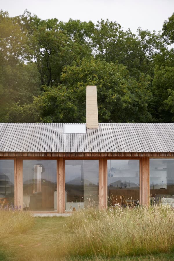 Architectural project - natural materials, wood, timber, grey, natural light, sustainable design, glass, natural tones, neutral tones, daylight, beige, wood facade, timber facade, light wood, eco friendly, honey wood, rustic modern, serene atmosphere, minimalist design, low carbon, modern rustic, biophilic design, open landscape, passive house, nature view, clean lines, large windows, indoor outdoor, timber cladding, wood cladding, Nordic style, energy efficient, earthy tones, sloped roof, pitched roof, wooden roof, peaceful vibe, wooden structure, green surroundings, simple lines, glass facade, rural house, country home, glazing, meadow, Scandinavian inspiration, elongated form, integrated architecture, connection with nature