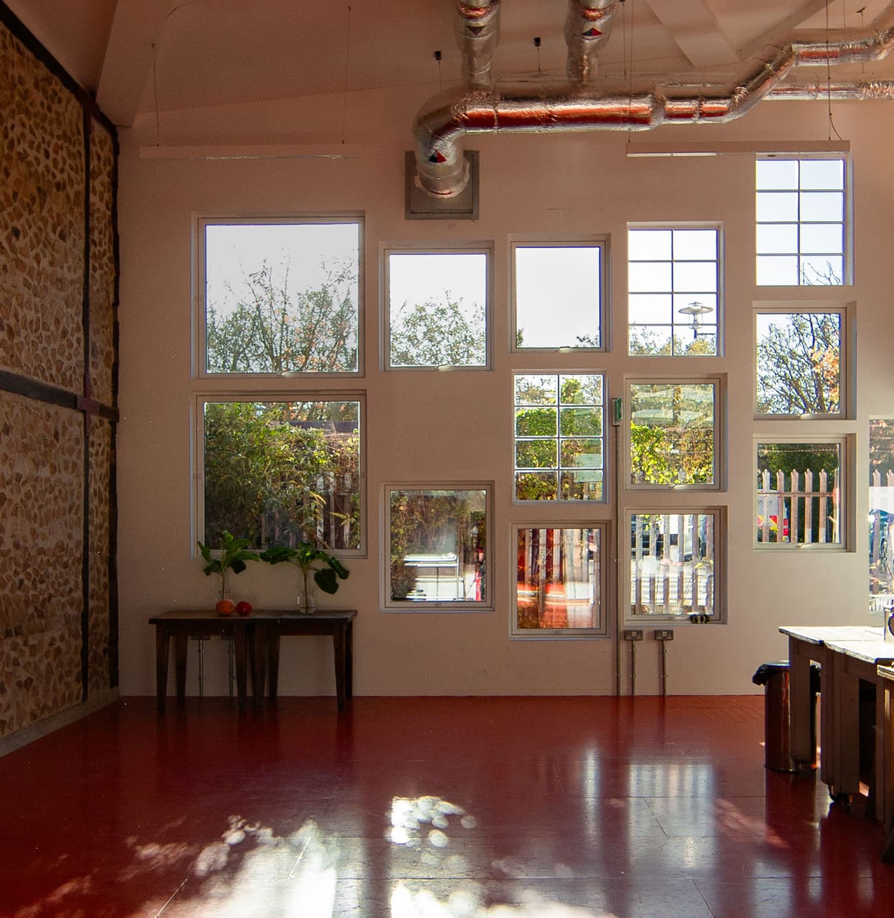 Architectural project - metallic finishes, grid windows, workshop, modern industrial, exposed ductwork, loft style, vibrant atmosphere, red floor, exposed stone, creative studio, studio, metal ducts, glossy floor, upcycled decor, airy interior, urban aesthetic, eclectic design, sustainable space, unique windows, farmhouse touch, light brick, organic elements, natural light, recycled materials, eco design, grey, daylight, industrial vibe, multifunctional space, eco friendly, rustic charm, contemporary design, casual setting, creative space, workspace, large windows, white, window view, open plan, stone wall, rustic wall, cozy corner, bright space, concrete floor, industrial space, indoor plants, mixed materials, versatile space, high ceiling, red, modular elements