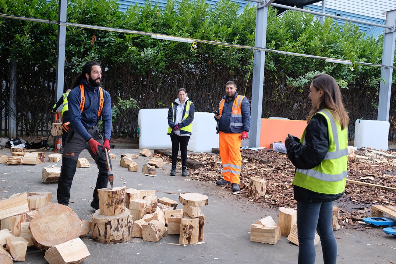 Architectural project - outdoor workshop, outdoor work, tree chopping, wood chopping, workwear, protective clothing, hi-vis vest, high visibility, chainsaw, lumberjack, wood logs, timber pieces, woodcutting, training session, industrial environment, forest backdrop, urban forestry, sustainable practice, eco activity, manual labor, learning session, environmental education, safety, training, sustainable, forest, community, wood, timber, safety gear, teamwork, collaboration, outdoor setting, eco friendly, outdoor, outdoor activity, nature integration, community project, professional training