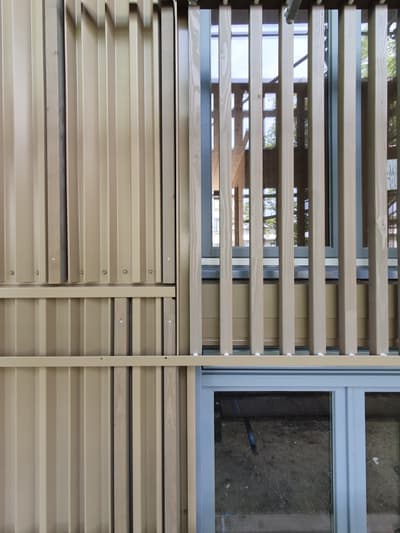 Architectural project - facade, metal accents, outdoor facade, building exterior, minimal design, natural materials, architectural design, sustainable materials, wood, timber, natural light, glass, warm tones, eco design, daylight, beige, building facade, architectural facade, geometric pattern, light wood, natural wood, eco friendly, sunlight, honey wood, contemporary design, neutral palette, exterior, urban design, structural detail, building materials, green architecture, biophilic design, modern facade, clean lines, timber cladding, wood cladding, modern architecture, sustainable facade, honey tones, wooden slats, innovative facade, vertical slats, architectural rhythm, texture contrast