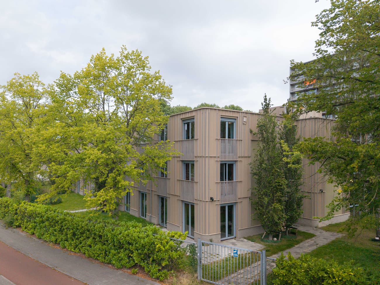 Architectural project - beige facade, residential complex, tree-lined, community living, multi-family housing, natural materials, sustainable materials, outdoor space, passive design, green building, contemporary architecture, sustainable architecture, green, neutral tones, beige, low carbon design, daylight optimization, eco friendly, urban oasis, urban design, eco building, sustainable building, biophilic design, residential development, modern facade, landscape integration, timber cladding, energy efficient, green living, energy saving, vertical cladding, modern exterior, green space, vertical panels, natural surroundings, apartment building, urban housing, modern residential