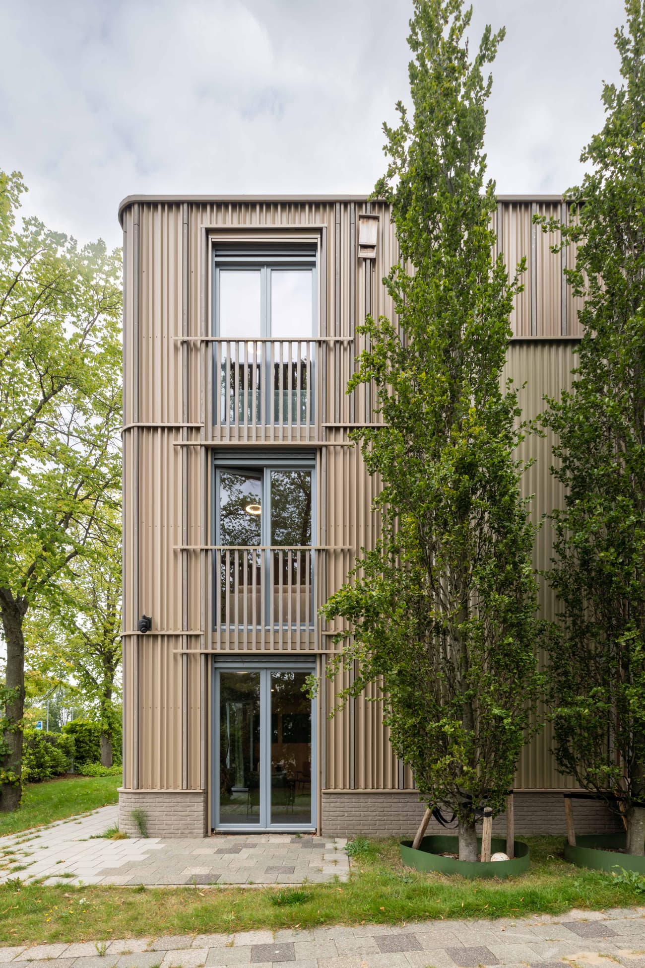 Architectural project - urban greenery, apartment facade, vertical elements, vertical lines, ribbed texture, ribbed cladding, natural design, tree-lined, high rise, vertical structure, eco friendly facade, architectural detail, contemporary architecture, beige, timber facade, minimalist architecture, light brown, neutral colors, eco materials, modern aesthetics, biophilic design, sustainable home, natural ventilation, modern facade, wood cladding, wood detailing, energy efficient, beige tones, green living, compact design, earthy tones, nature-inspired, greenery, green design, eco architecture, residential building, modern home, balcony design, sleek design, passive solar, aluminum windows, facade rhythm, city dwelling, urban living, vertical garden