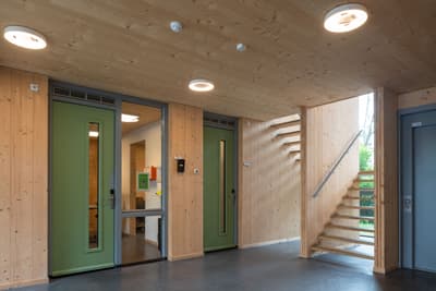 Architectural project - open stair, interior door, green doors, simple interior, natural materials, wood, timber, natural light, warm tones, eco design, contemporary style, grey, green, neutral tones, functional space, wooden ceiling, beige, brown, light wood, natural wood, modern aesthetic, daylight optimization, eco friendly, Scandinavian style, minimalist design, glass doors, sustainable building, timber walls, wood panels, sustainable home, passive house, clean lines, cozy vibe, energy efficient, wood walls, timber ceiling, compact design, inviting space, warm atmosphere, bright interior, efficient layout, nordic influence, residential, home interior, wooden stairs, clean design, stairwell
