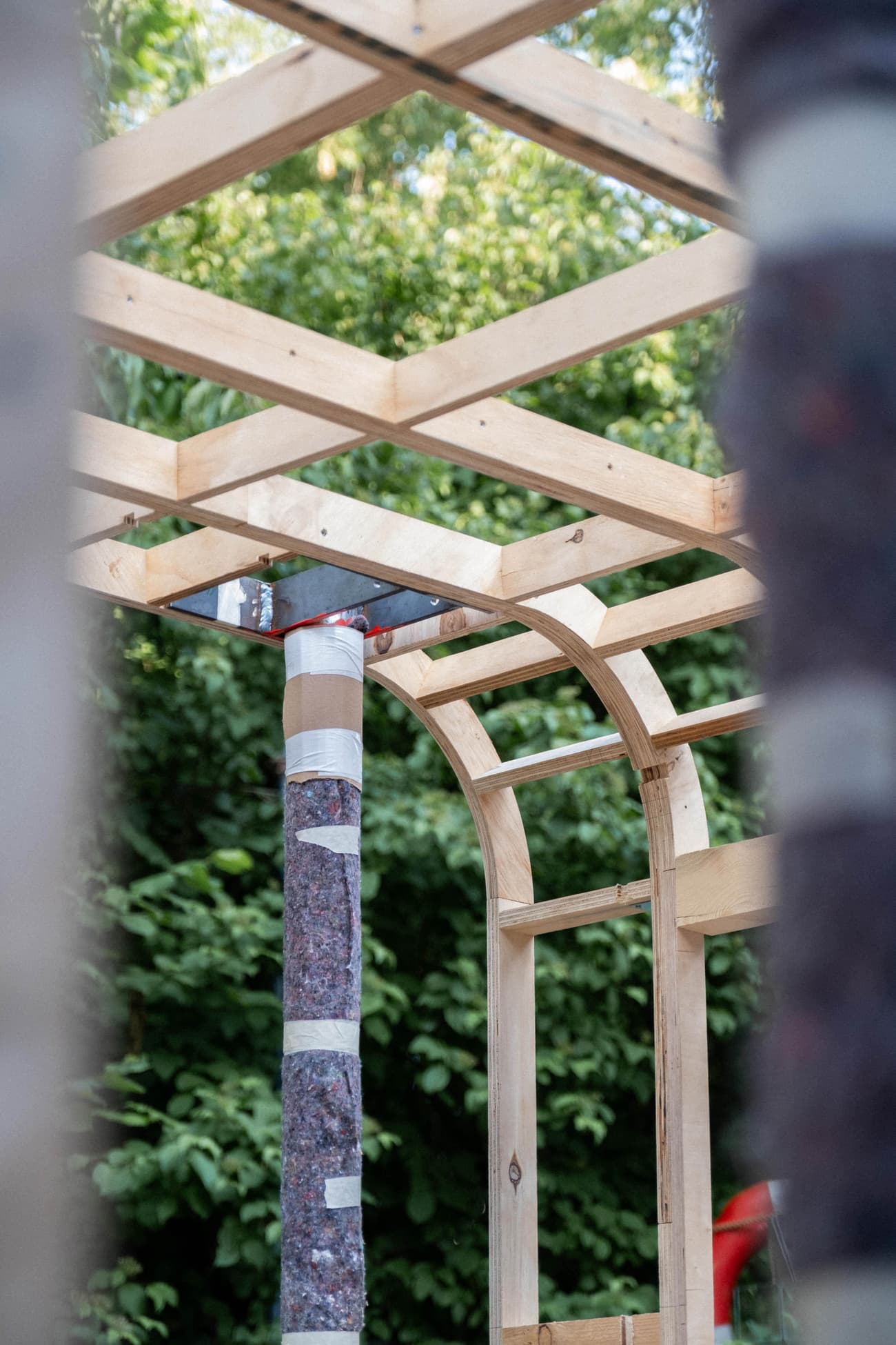 Architectural project - sustainable build, arch beams, exposed frame, unfinished construction, garden background, construction elements, natural timber, green environment, timber joints, bright light, wood joints, timber columns, garden architecture, simple build, airy structure, outdoor frame, timber arch, natural materials, sustainable materials, raw materials, timber frame, passive design, warm tones, modular design, simple structure, structural timber, outdoor construction, outdoor setting, light wood, wooden beams, timber beams, timber building, wood structure, eco construction, low carbon, biophilic design, nature integration, green design, eco architecture