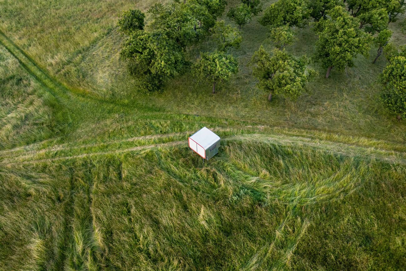 Architectural project - untouched nature, harmony with nature, self-sufficient, site-specific, tiny house, grass, small cabin, micro dwelling, white cube, cubic shelter, isolated home, grassy fields, pastoral view, secluded spot, tranquil scene, modern shelter, outdoor solitude, peaceful environment, temporary shelter, stark contrast, minimal design, eco-friendly design, passive design, eco design, green, rural architecture, minimalist retreat, minimalist style, lightweight materials, lightweight structure, geometric design, green landscape, white, energy efficient, simple living, rural setting, countryside, nature escape, off-grid living, compact living, environmental harmony, natural surroundings, simple form, sustainable living, meadow
