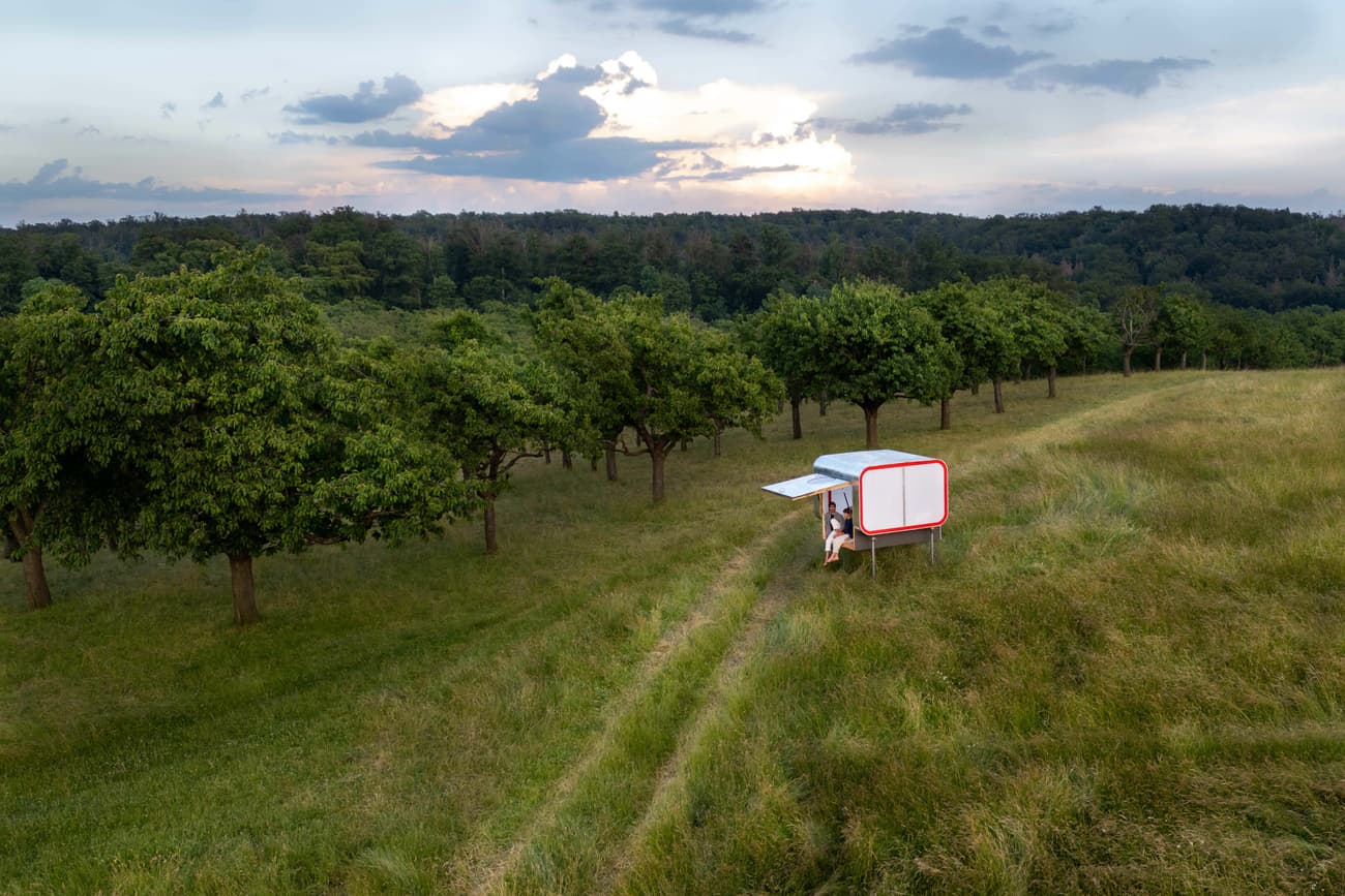 Architectural project - portable dwelling, scenic backdrop, micro shelter, minimal shelter, rural escape, meadow setting, mobile cabin, prefabricated unit, minimal impact, solar panel, meadow view, rolling hills, nature getaway, unplugged retreat, rural lifestyle, simple shelter, basic living, regenerative design, steel, outdoor living, modular design, contemporary style, sustainable architecture, green, eco friendly, modern simplicity, minimalist design, lightweight structure, low carbon, clean lines, green landscape, white, energy efficient, compact design, nature connection, peaceful vibe, off-grid living, serene setting, countryside retreat, open space, renewable energy, sustainable living, meadow, natural beauty, tiny home, red, efficient space