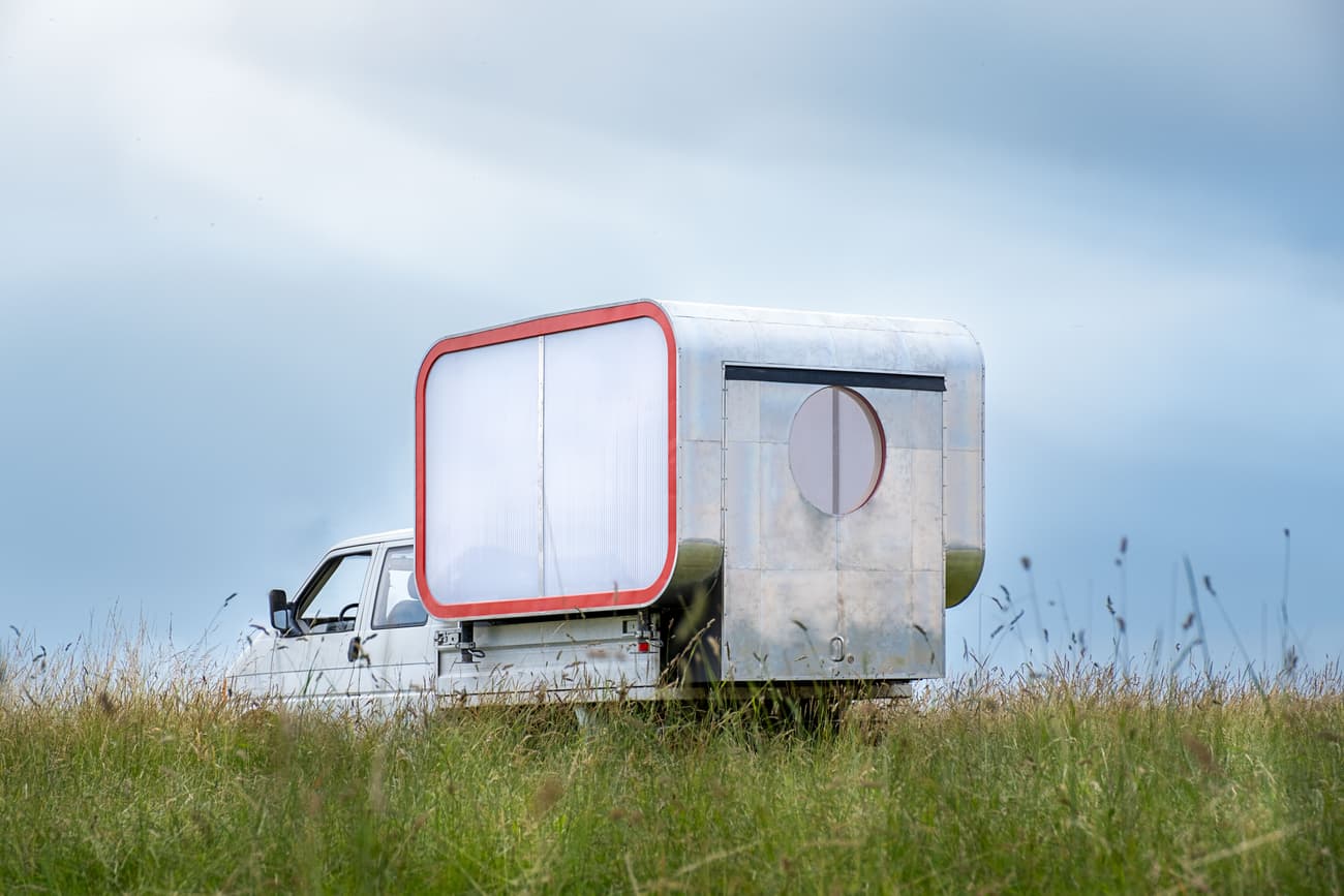 Architectural project - mobile home, tiny house, nomadic lifestyle, portable home, minimalist lifestyle, travel home, modern caravan, metallic finish, travel trailer, light grey, caravan design, minimalist camper, futuristic design, minimal lines, DIY camper, aluminum siding, metal exterior, geometrical design, adventure home, sustainable travel, eco-friendly vehicle, low impact travel, road trip home, exploration vehicle, open road living, green grass, outdoor adventure, travel minimalism, contemporary camper, exploration travel, metallic, round window, grey, outdoor living, sustainable design, innovative design, lightweight construction, multifunctional space, blue sky, white, green living, compact design, panoramic view, simple living, nature escape, off-grid living, compact living, curved design, natural surroundings, spacious feel, versatile space, red