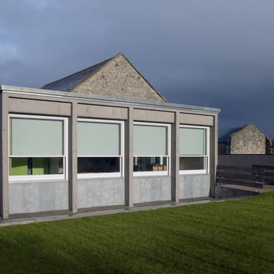 Architectural project - rectangular shape, grey facade, modern renovation, educational facility, concrete facade, stone building, utilitarian, concrete building, minimal design, outdoor space, natural light, passive design, eco design, sustainable construction, community space, grey, green, concrete, minimalist facade, low carbon design, functional design, daylight optimization, flat roof, contemporary design, green architecture, modern facade, clean lines, large windows, energy efficient, stone, stone wall, school building, educational building, school renovation, green space, educational architecture, outdoor learning, schoolyard, modern school, simple form, school architecture, practical design, lawn area