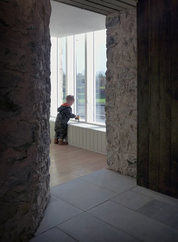 Architectural project - exposed stone, heritage preservation, rugged texture, Scandinavian touch, textural contrast, restoration, heritage site, intimate space, serene vibe, architectural detail, wood, timber, natural light, inviting atmosphere, warm tones, grey, neutral tones, daylight, beige, brown, rustic charm, calm ambiance, minimalist design, raw texture, modern rustic, large window, stone, cozy nook, family space, stone wall, rustic wall, child friendly, timber panel, minimalist aesthetic, nordic influence, residential, home, interior space, vertical slats, soft light, indoor, renovation, wood panel, play area