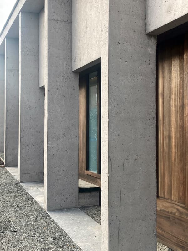 Architectural project - exposed concrete, geometric lines, raw concrete, vertical lines, grey facade, wooden doors, concrete facade, minimal vibe, grey concrete, brutalist architecture, brutalist, sustainable materials, wood, timber, outdoor space, sustainable design, modular design, grey, brown, concrete, architectural elements, exterior wall, industrial style, low carbon design, functional design, daylight optimization, natural textures, contemporary design, minimalist design, open facade, urban design, passive house, natural ventilation, modern facade, clean lines, architectural simplicity, energy efficient, wood accents, timber accents, earthy tones, eco-friendly building, sleek design, facade design, concrete wall, structural rhythm, contemporary building