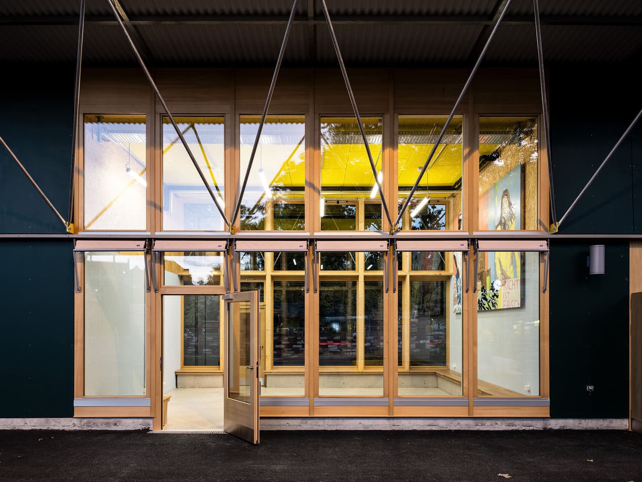 Architectural project - urban building, geometrical design, public access, community building, glass elements, transparency, exposed framework, materials emphasis, metal accents, welcoming entrance, wood, timber, steel, natural light, glass, warm tones, grey, neutral tones, timber structure, daylight, city architecture, beige, timber facade, architectural facade, modern aesthetic, engineered wood, functional design, eco friendly, contemporary design, industrial touch, sustainable building, modern facade, clean lines, modern architecture, compact design, exterior view, green design, eco architecture, minimalist exterior, sleek design, wooden structure, structural elements, public building, glass facade, urban vibe, architectural innovation, efficient space