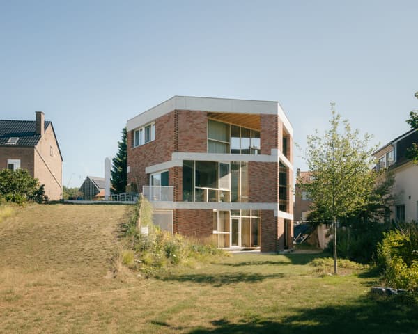 Architectural project - floor to ceiling windows, light wood accents, angular design, brickwork, architectural home, symmetrical design, minimal design, natural materials, timber, outdoor space, natural light, outdoor living, glass, warm tones, modern vibe, green, neutral tones, daylight, beige, concrete, exterior design, eco friendly, sustainable building, thermal mass, contemporary home, modern facade, clean lines, large windows, white, inviting home, modern architecture, energy efficient, open plan, brick, landscape design, brick facade, garden view, cozy exterior, family home, residential building, passive solar, suburban home, lawn area, urban home, geometric form, red