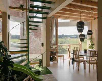 Architectural project - floor to ceiling windows, brick wall, wooden chairs, round table, pendant lights, living dining area, modern lighting, wood, timber, natural light, sustainable design, glass, warm tones, contemporary style, green, neutral tones, exposed beams, daylight, beige, brown, light wood, multifunctional space, timber beams, rustic modern, Scandinavian style, modern rustic, passive house, nature view, large windows, Nordic design, eco friendly home, cozy vibe, timber accents, stone, countryside view, airy space, open layout, open plan, inviting space, warm atmosphere, casual dining, brick, red brick, greenery, bright interior, family home, wood ceiling, home interior, playful space, ceramic, indoor plants
