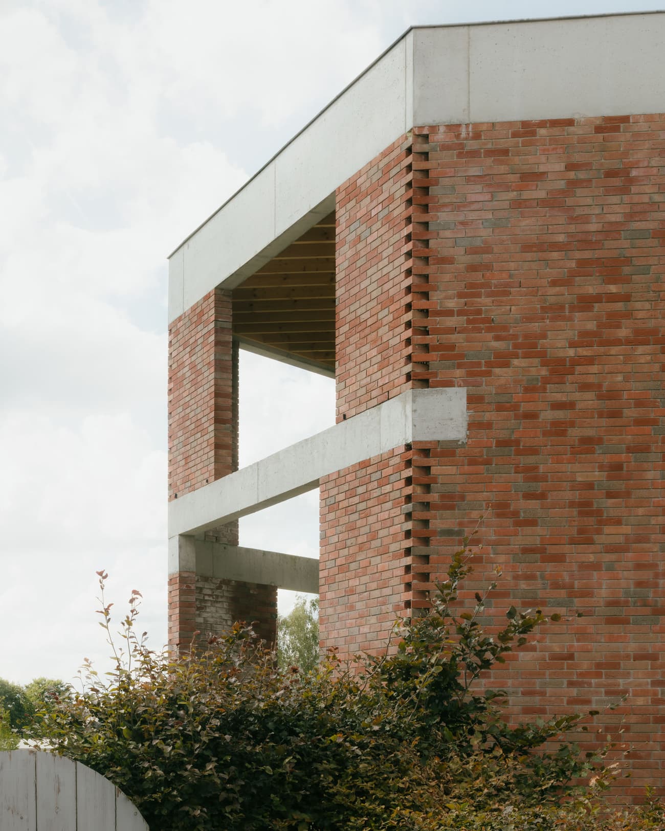 Architectural project - facade articulation, airy structure, custom design, brick wall, exposed brick, plant life, raw material, structural clarity, light play, passive design, warm tones, eco design, contemporary architecture, sustainable architecture, grey, green, neutral tones, beige, architectural facade, exterior wall, low carbon design, natural setting, outdoor structure, rustic vibe, minimalist design, geometric design, textured surface, natural ventilation, framed view, terracotta, environmentally friendly, brick facade, red brick, greenery, earthy palette, residential building, modern home, modernist style, urban architecture, facade design, facade texture, red